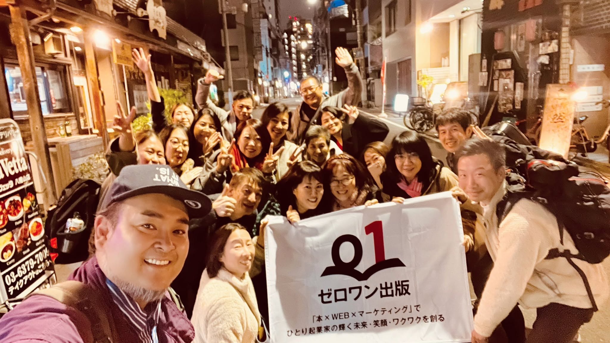 ゼロワン出版の旗を囲んで集まった人たち